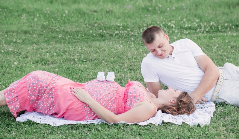 pregnant couple lying in the grass_New_Love_Times