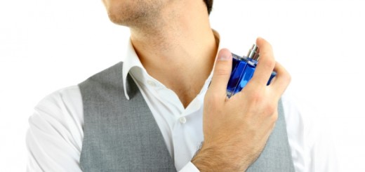 Handsome young man using perfume isolated on white